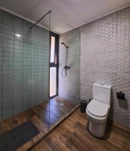 a bathroom with a toilet and a glass shower at Wine Lodge de Viña Vultur en bosque nativo con piscina in Doñihue
