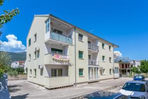 un edificio bianco con balcone e auto parcheggiate in un parcheggio di Apartments with a parking space Kastel Stari, Kastela - 17964 a Kaštela (Castelli)