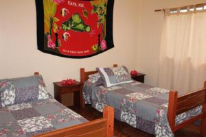 1 dormitorio con 2 camas y una foto en la pared en Camping Hostal Tipanie Moana Aeropuerto Centro en Hanga Roa