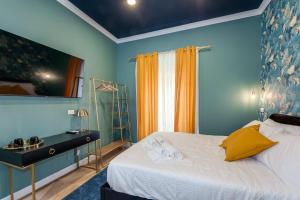 Schlafzimmer mit blauen Wänden und einem Bett mit gelben Kissen in der Unterkunft Suri Suites in Rom
