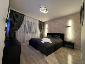 een slaapkamer met een zwart bed en een groot raam bij Impact Apartments in Piteşti