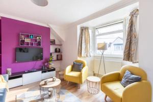 a living room with purple walls and yellow chairs at cosy 1 bedroom flat near Barking town centre in Barking