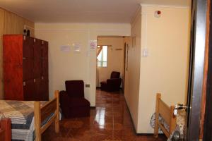 um quarto com uma cama e uma cadeira e um corredor em Camping Hostal Tipanie Moana Aeropuerto Centro em Hanga Roa