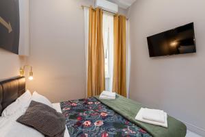1 dormitorio con 1 cama y TV en la pared en Empire Suites, en Roma