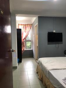 a bedroom with a bed and a television on the wall at FAMILY HOTEL in Kuala Kubu Baharu