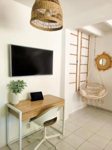 un bureau à domicile avec un bureau et une télévision au mur dans l'établissement Studio double climatisé avec terrasse - Proche Tram & Centre, à Montpellier