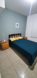 a bedroom with a blue bed and a table at Departamentos en Playa Pulpos HOSPEDAJE DELFINES HOUSE in Lurín