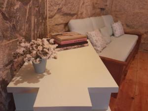 Una mesa blanca con un sofá y flores. en Ninho do Corvo da Urgueira, en Urgueira
