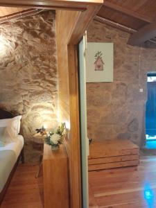 1 dormitorio con cama y pared de piedra en Ninho do Corvo da Urgueira, en Urgueira