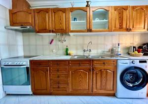 a kitchen with wooden cabinets and a washing machine at Quarteira Paul Harris Apartment in Quarteira