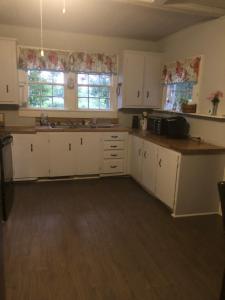 an empty kitchen with white cabinets and windows at Private Cottage in Rural Setting in Clemmons