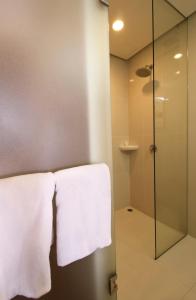 マニラにあるRed Planet Makati Amorsoloのバスルーム(ガラス張りのシャワー、白いタオル付)