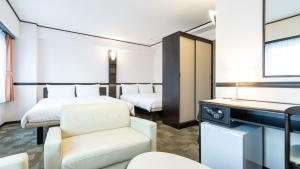 una camera d'albergo con due letti e una sedia di Toyoko Inn Kakegawa eki Shinkansen Minami guchi a Kakegawa