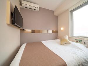 een slaapkamer met een bed en een televisie aan de muur bij Super Hotel Premier Akasaka in Tokyo