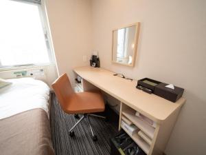 Schlafzimmer mit einem Schreibtisch, einem Bett und einem Spiegel in der Unterkunft Super Hotel Premier Akasaka in Tokio