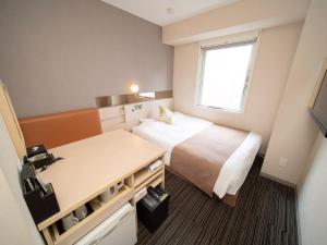 Habitación pequeña con cama y escritorio. en Super Hotel Premier Akasaka en Tokio