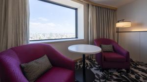 名古屋市にあるANAクラウンプラザホテルグランコート名古屋の椅子2脚、テーブル、窓が備わる客室です。