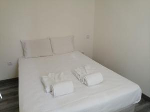 a white bed with two white towels on it at Cantinho da Karine in Maia