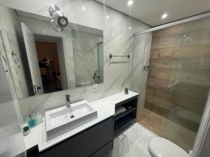 a white bathroom with a sink and a shower at Flat Premium -Acesso a pé ao shopping Center vale - Edifício Summit (Ar condicionado) in São José dos Campos