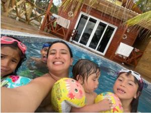 Villa Devonia - Beachfront Cabins with Pool at Tela, HN في تيلا: امرأة وثلاث اطفال في مسبح
