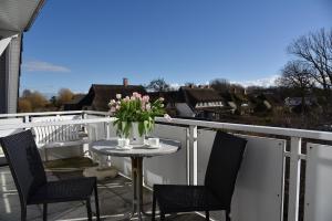 a patio table with chairs and flowers on a balcony at Ferienwohnung im Blauen Haus in Ahrenshoop