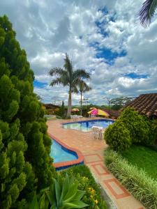 a swimming pool in a yard with a palm tree at Hotel Campestre La Primavera del Quindío in Montenegro