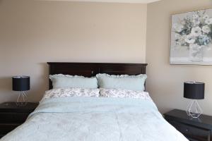 a bedroom with a white bed with two lamps on tables at Yucca Tree-Licensed in Kelowna