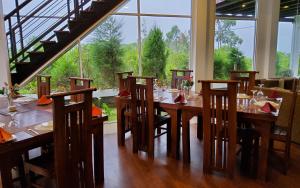een eetkamer met een tafel met stoelen en een groot raam bij Thimaya Resort in Hatton