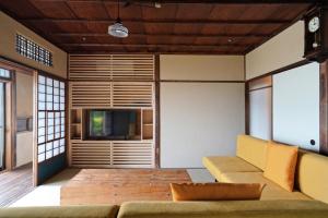 uma sala de estar com um sofá e uma televisão em new! 熱海桃山邸　Atami terrace villa 〜Sauna & Onsen 〜 em Atami