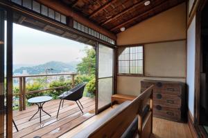 a room with a balcony with a table and a chair at new! 熱海桃山邸　Atami terrace villa 〜Sauna & Onsen 〜 in Atami