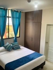 um quarto com uma cama com cortinas azuis e uma janela em Reef Hostel Manta em Manta