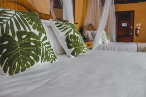 a bed with green and white pillows on it at The Mayan Garden in Orange Walk