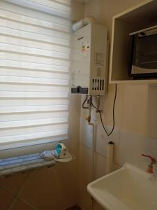 a small kitchen with a microwave and a sink at Chillan Centro in Chillán
