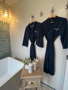 ein Badezimmer mit zwei Hemden, die an einer Wand neben einer Badewanne hängen in der Unterkunft Seaside Serenity Cottage in Shelburne