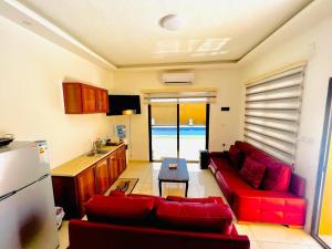 a living room with a red couch and a kitchen at Al Andalus Chalets ‏ in Shūnat Nimrīn