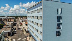 un edificio blanco alto junto a una calle de la ciudad en Hotel Arezzu, en Linhares