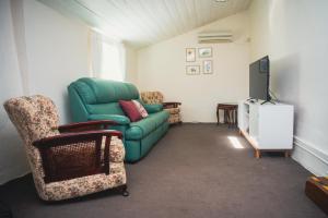 a living room with a green couch and a tv at Kooringa Cottage in Burra