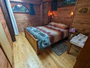 a bedroom with a bed in a wooden cabin at Rivendell Farmstay Hobbit Hole in Cambridge