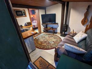 a living room with a couch and a television at Rivendell Farmstay Hobbit Hole in Cambridge