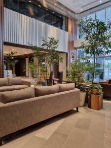 a lobby with couches and plants in a building at Brittany Hotel BGC in Manila