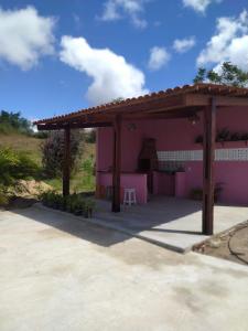 une maison rose avec une pergola en bois dans l'établissement Chalés Rosados, à Serra de São Bento