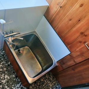 La salle de bains est pourvue d'un lavabo en métal et de murs en bois. dans l'établissement Madarao Farm, à Nakano