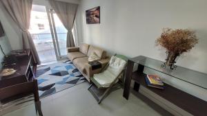 uma sala de estar com um sofá e uma mesa de vidro em Apartamento frente para a piscina a uma quadra da praia em Florianópolis