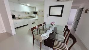 uma mesa de jantar de vidro com cadeiras e um vaso com flores em Apartamento frente para a piscina a uma quadra da praia em Florianópolis