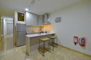 a kitchen with a refrigerator and a counter with stools at Wafa Hotel & Apartment in Kampong Mata Mata
