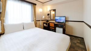 大阪市にある東横INNあべの天王寺のベッド、デスク、テレビが備わるホテルルームです。