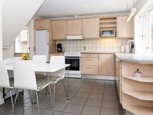 uma cozinha com uma mesa e cadeiras brancas em Holiday home Højer III em Højer