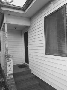a porch of a house with a window and stairs at The Cottage in Queanbeyan