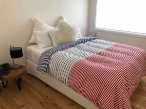a bedroom with a bed with a striped blanket and a window at The Cottage in Queanbeyan