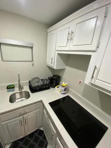 eine kleine Küche mit weißen Schränken und einem Waschbecken in der Unterkunft City View Luxury Home in Montego Bay